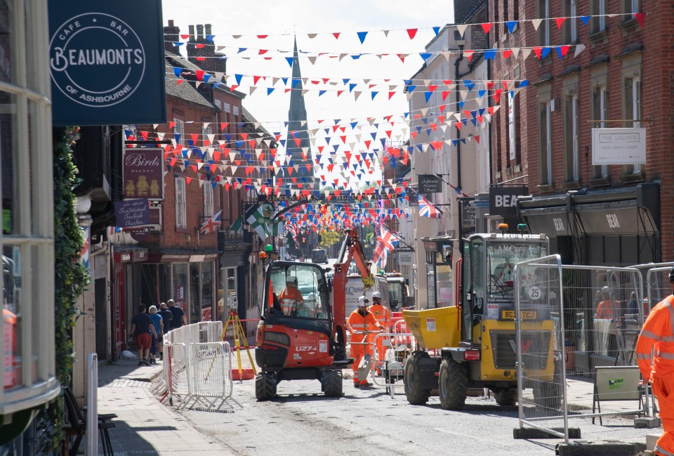 Roadworks in a small town, with construction equipment and workers present.