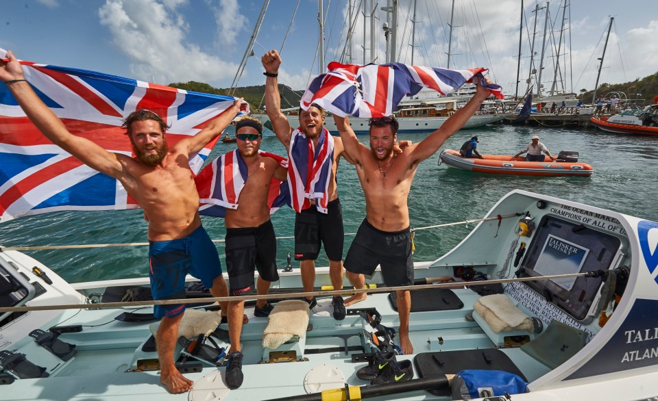 Four British rowers celebrating their victory in the Talisker Whisky Atlantic Challenge, holding Union Jack flags.