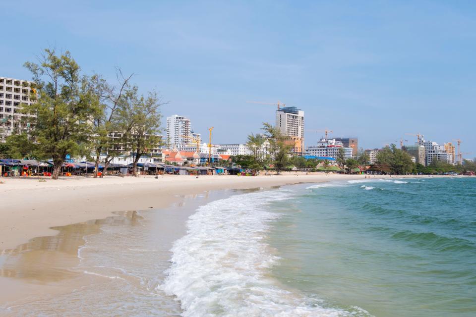 Beach in Sihanoukville, Cambodia, with buildings and construction cranes in the background.