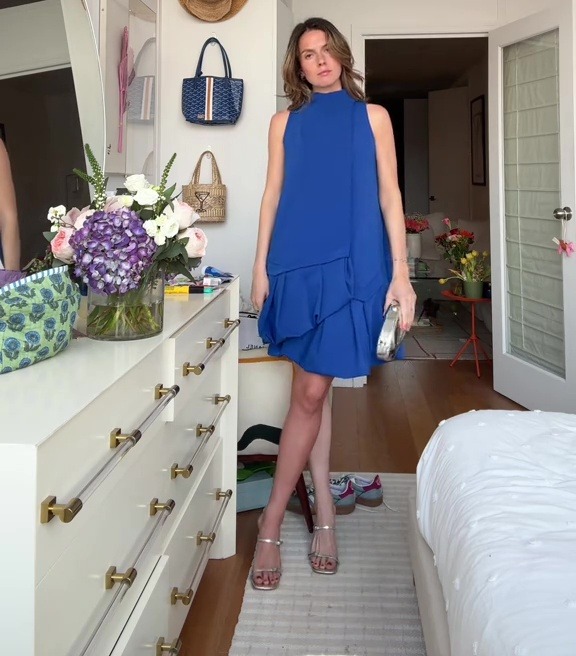 Woman in blue dress realizing she only tanned one leg.