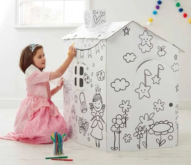 Girl coloring a cardboard playhouse.
