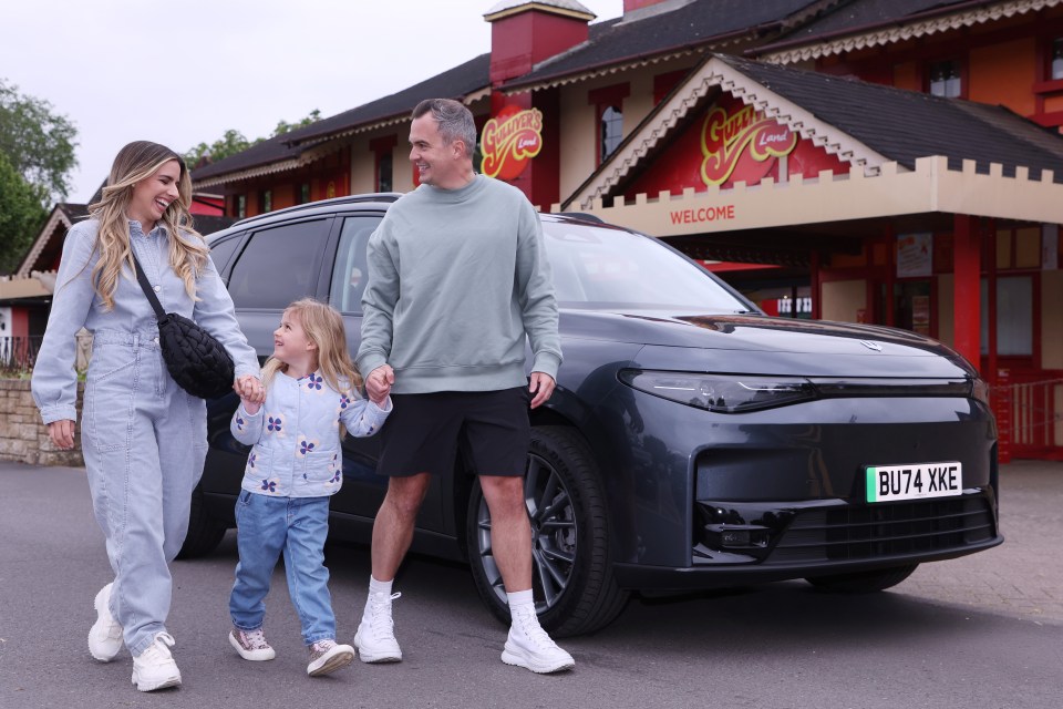 Family with young child standing by Leapmotor C10 electric car outside Gulliver's Land.