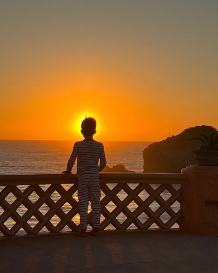 Child watching sunset over ocean.