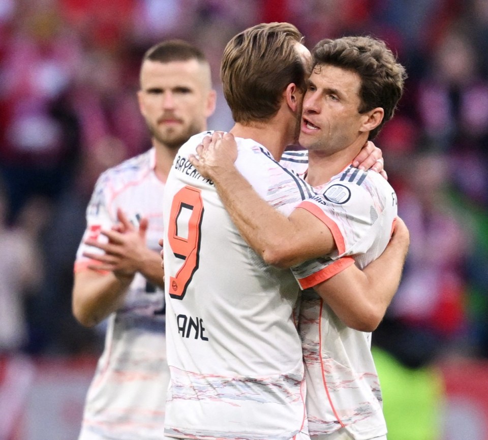 Thomas Müller and Harry Kane embracing on a soccer field.