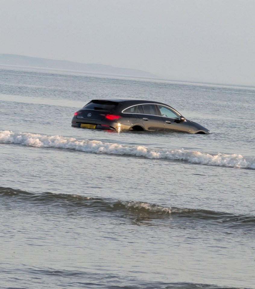 Car submerged in ocean waves.