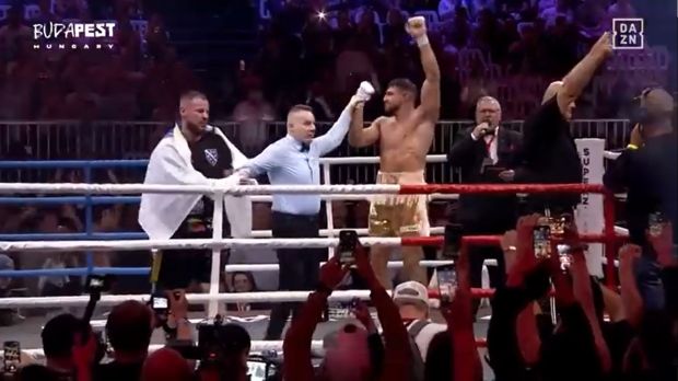 Boxer raises his hands in victory in a boxing ring.