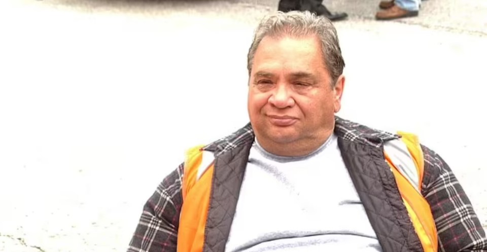 A man wearing a gray shirt and a black and orange vest.