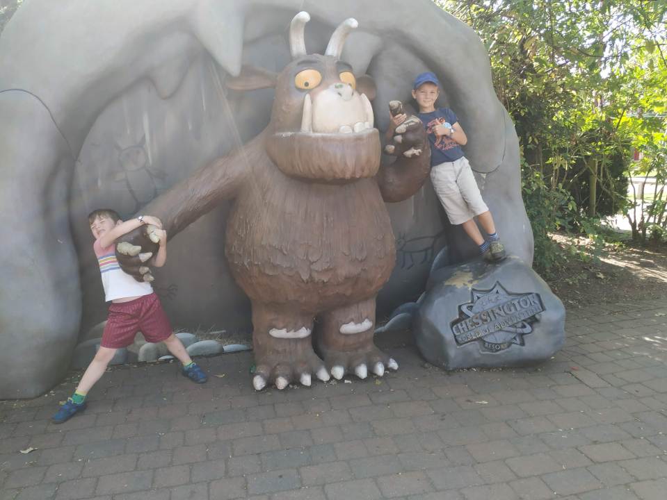 Two boys posing with a large Gruffalo statue at Chessington World of Adventures Resort.