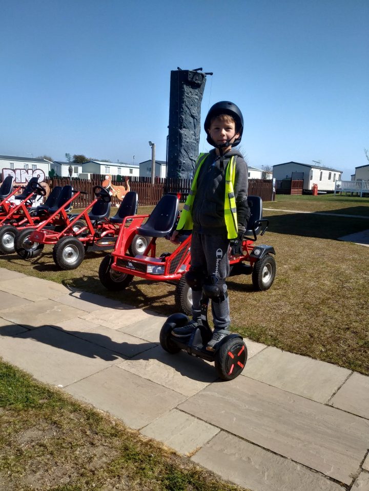 Boy on hoverboard near go-karts.