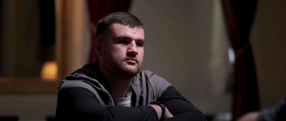 Man with arms crossed, sitting and looking pensive.
