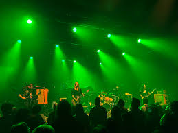 Band performing on stage in green light.