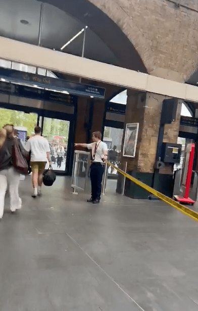 Screenshot of a train station with a staff member directing passengers.
