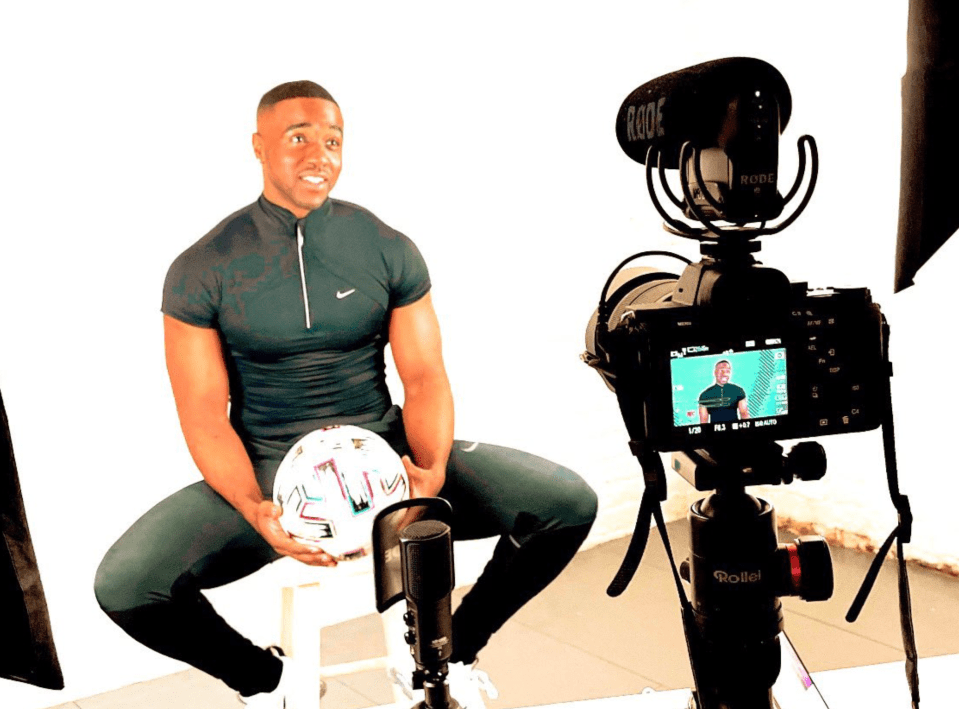 Man being interviewed on camera, holding a soccer ball.