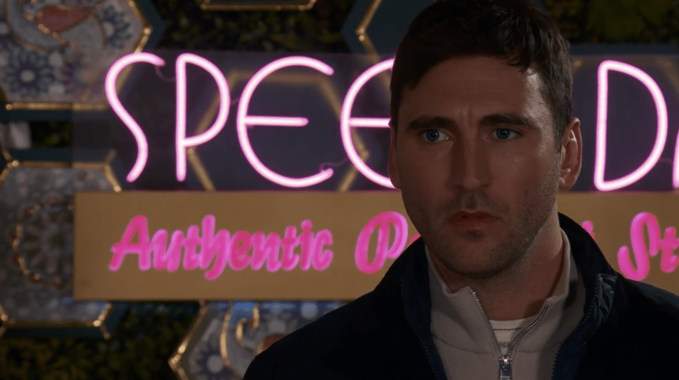 Man standing in front of a pink neon sign that says "Speed Authentic Pizza".