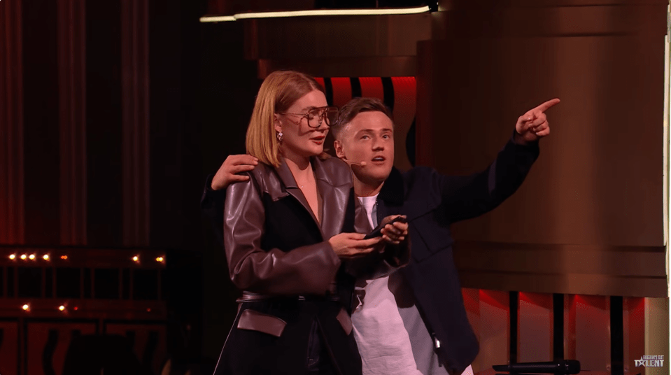 Screenshot of two people on a stage, one pointing.