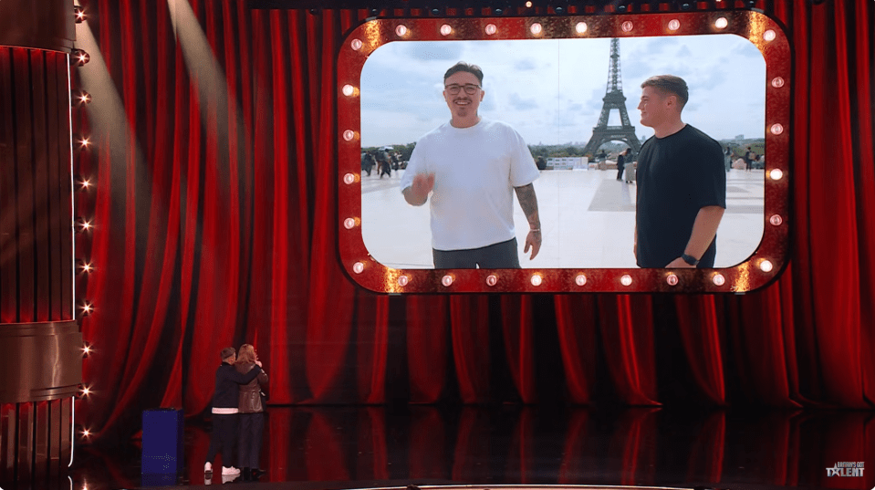 Screenshot of two men in Paris shown on a large screen on a stage.