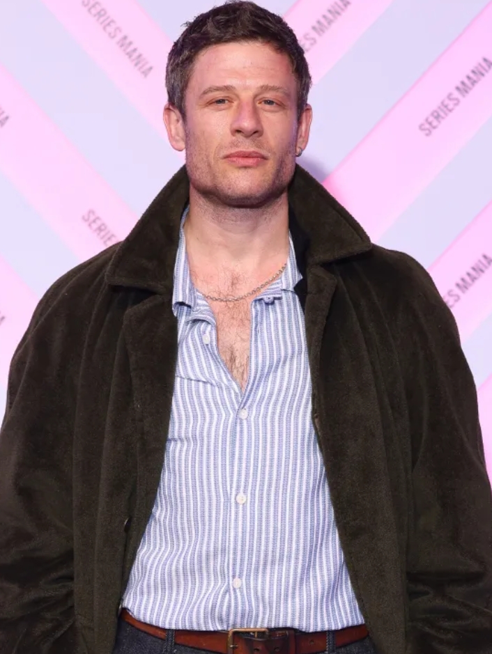 Headshot of a man wearing a dark jacket and light blue striped shirt.