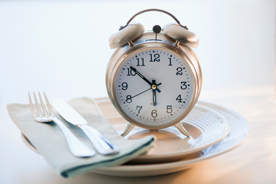 Alarm clock on a plate with silverware.
