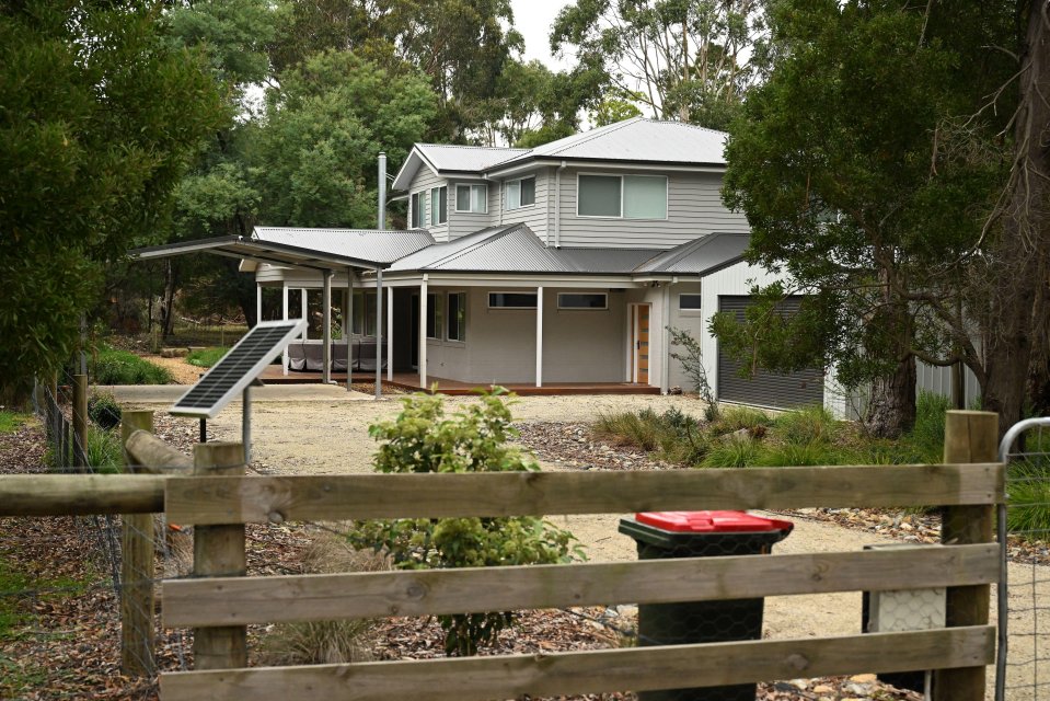 Exterior view of a two-story house with a gray metal roof and a solar panel.
