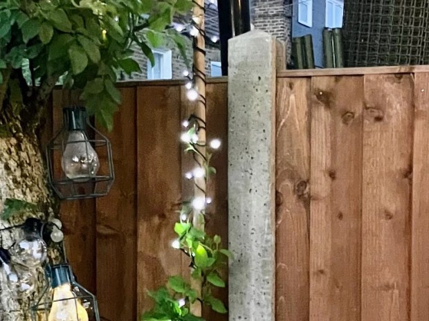 Solar string lights wrapped around a post next to a wooden fence.