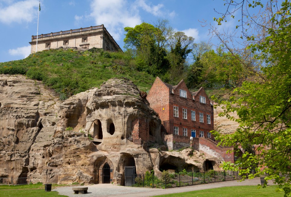 Nottingham Castle overlooking sandstone caves and a brick building.