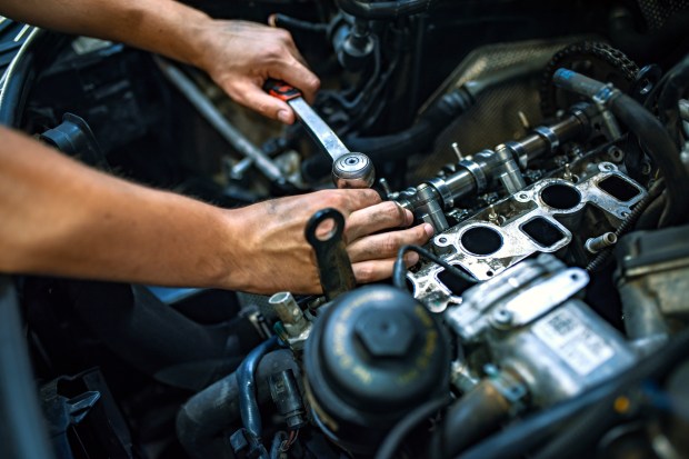 Close-up of a mechanic's hands repairing a car engine.