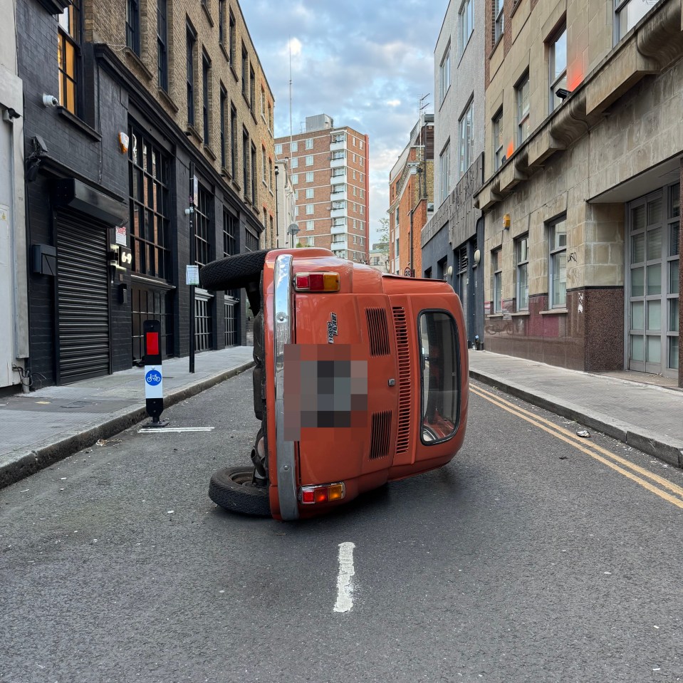An overturned classic car in a city street.
