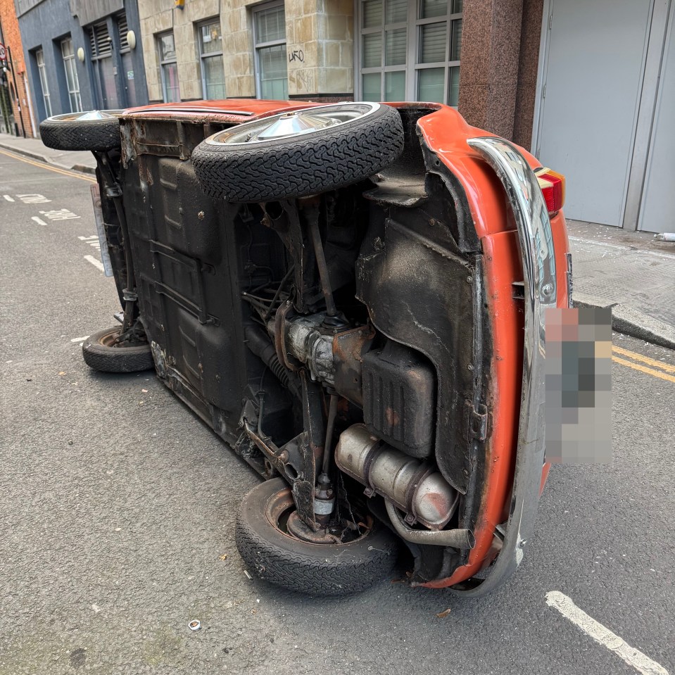 An overturned classic car in a street.