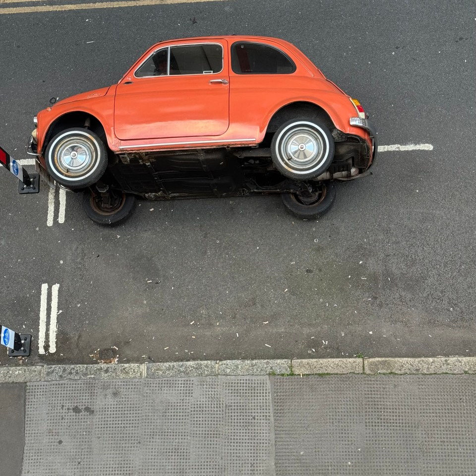 An orange Fiat overturned on a street.