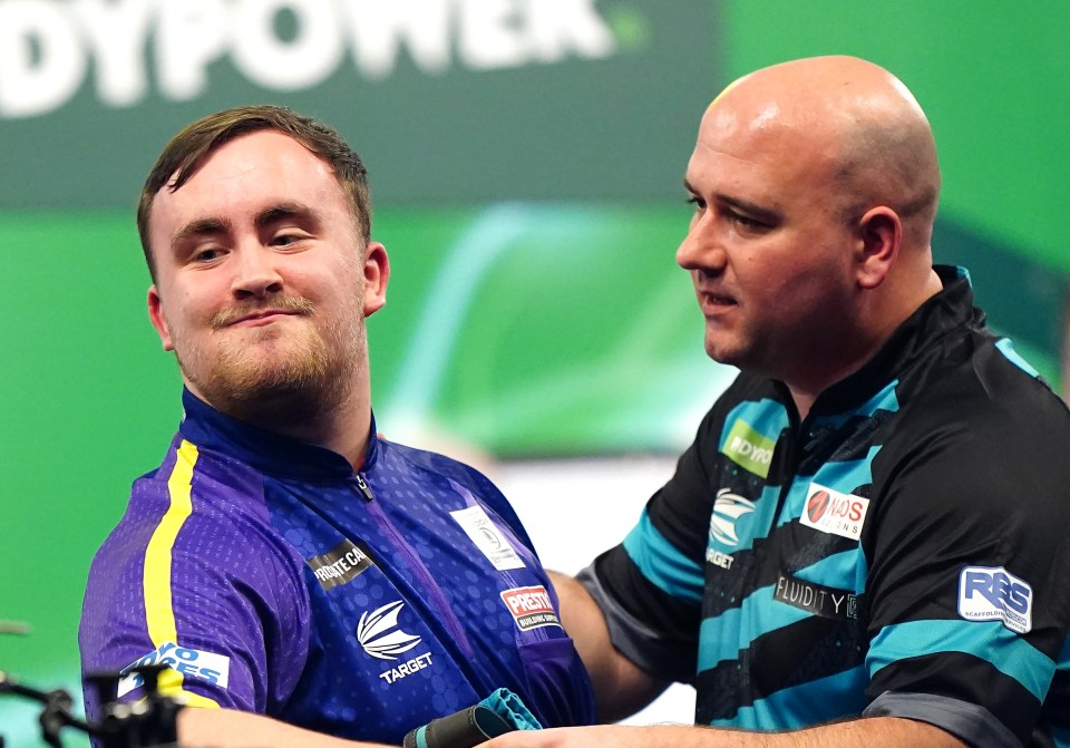 Luke Littler celebrates a darts victory with Rob Cross.