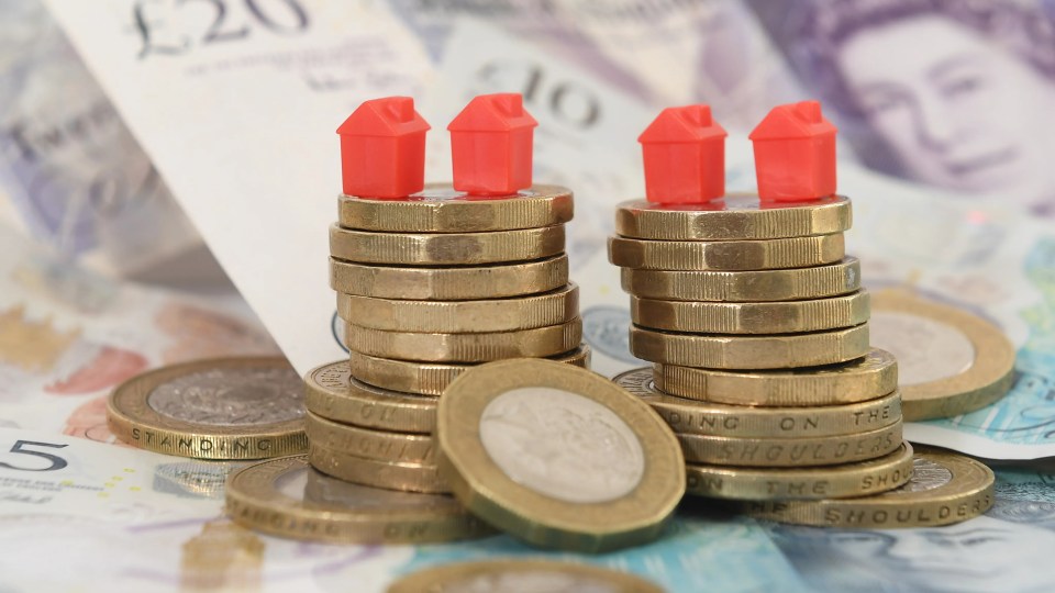 Model houses on stacks of coins atop banknotes.