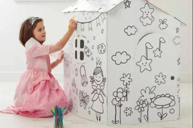 Girl coloring a cardboard playhouse.