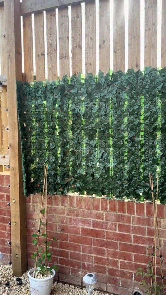 Artificial ivy privacy screen attached to a wooden fence.
