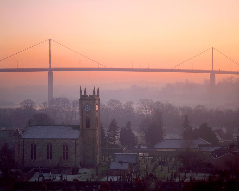 Church and graveyard at sunrise, with a bridge in the background.
