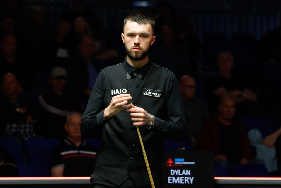 Dylan Emery chalking his cue during a snooker match.