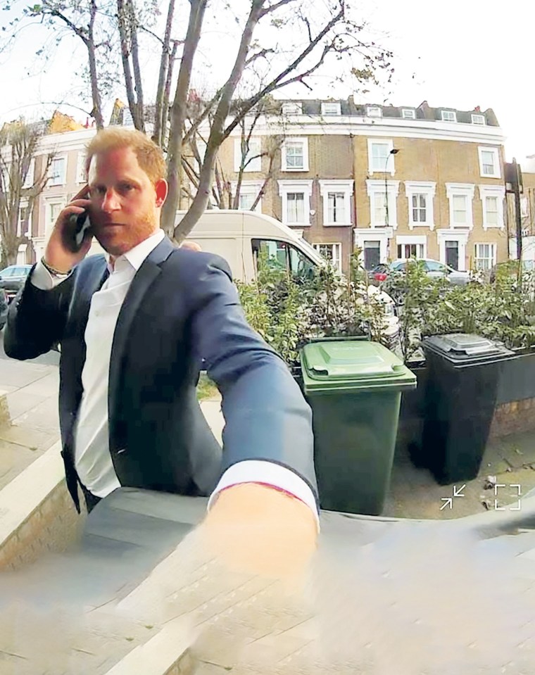 Prince Harry on a phone call outside a building in Fulham.