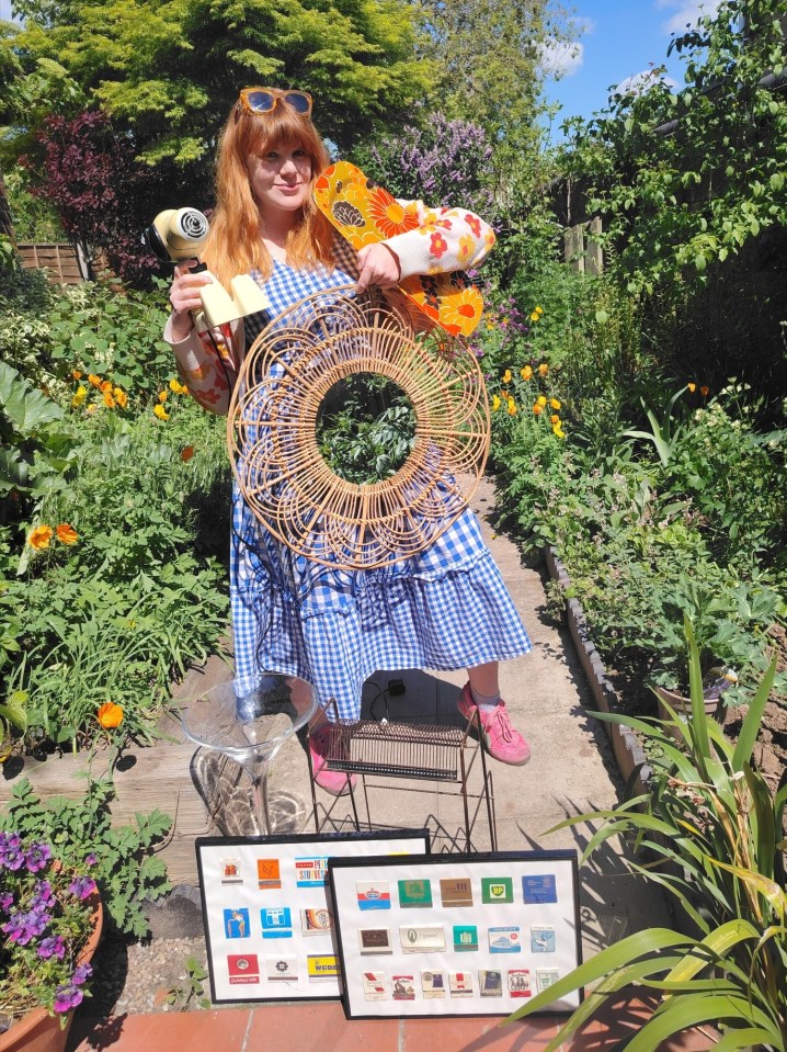 Woman in a garden holding vintage items for sale.