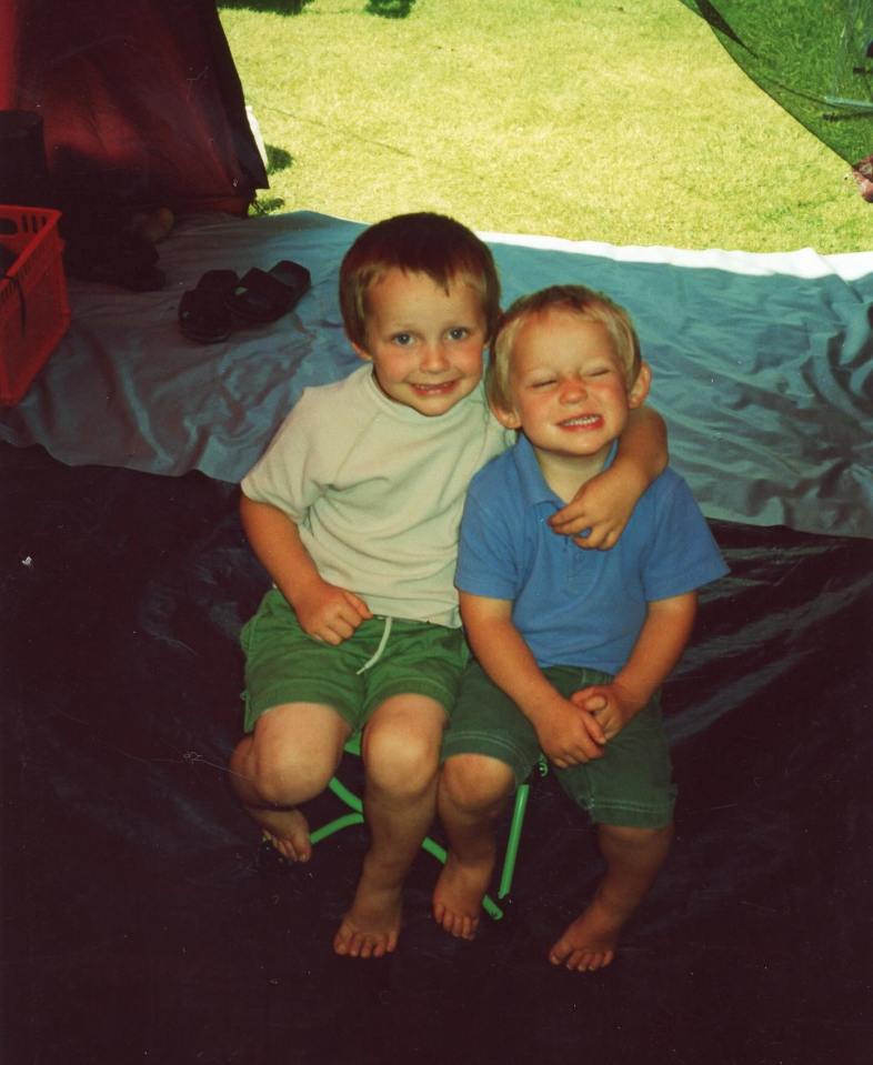 Two young boys sitting together inside a tent.