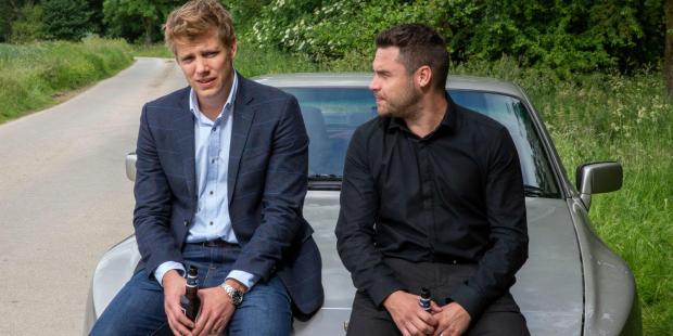 Aaron Dingle and Robert Sugden sitting on a car.