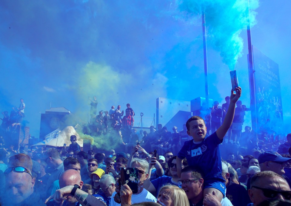 Everton FC fans with blue flares outside Goodison Park.