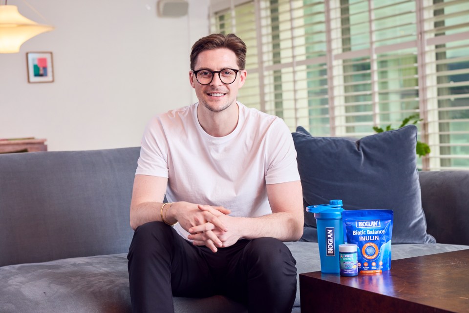 Dr. Alex George sitting on a couch with Bioglan products.
