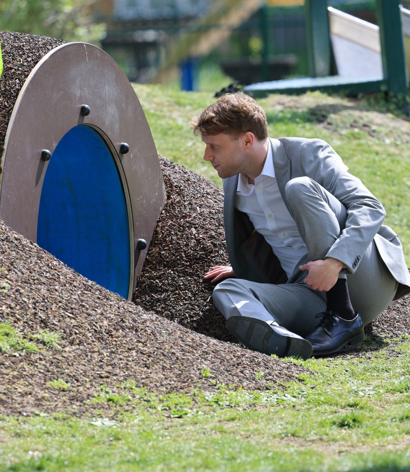 Man in suit looking into a play tunnel.