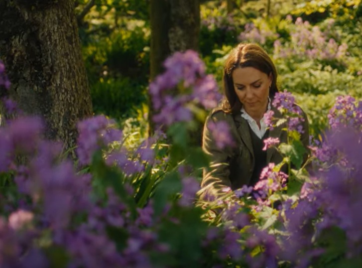Woman tending to purple flowers in a garden.