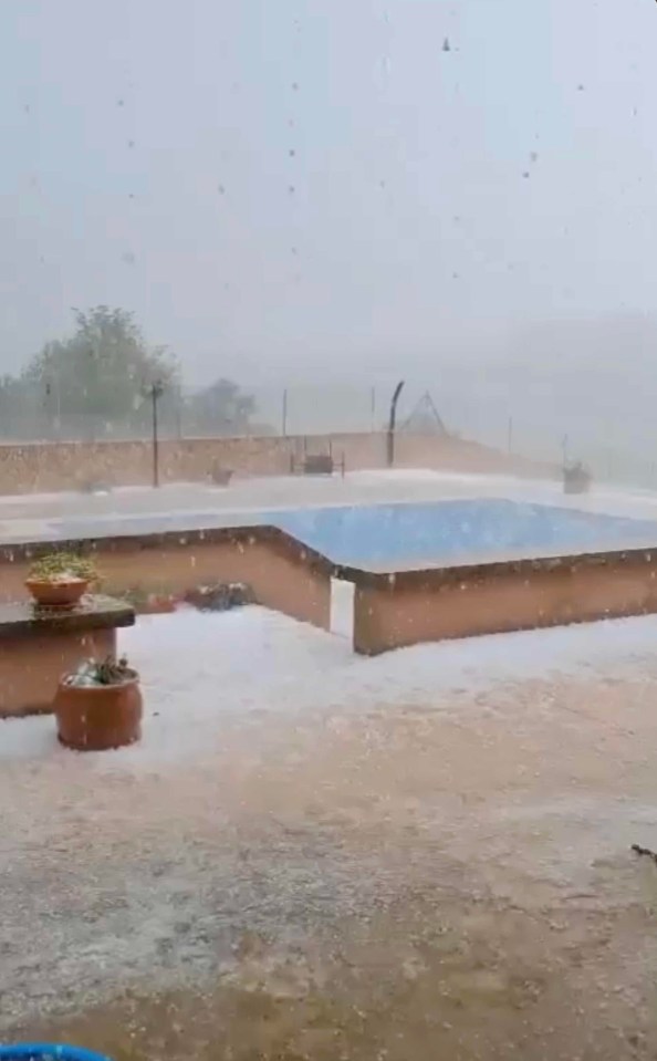 Hailstorm covering a pool and patio area.