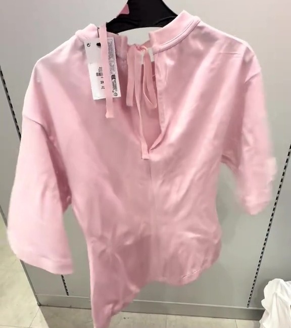Pink cinch waist T-shirt on a hanger.