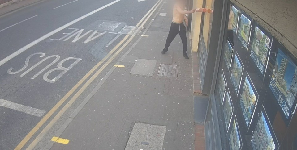 CCTV image of a man smashing shop windows with a fire extinguisher.
