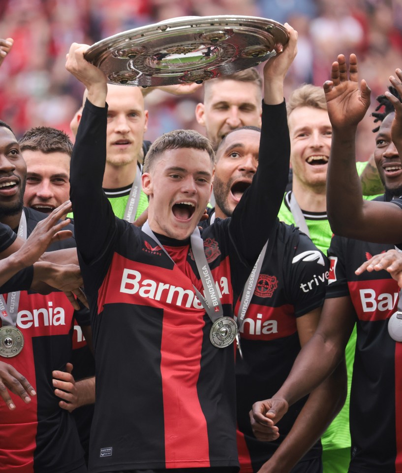 Florian Wirtz of Bayer Leverkusen holding the Bundesliga championship trophy.