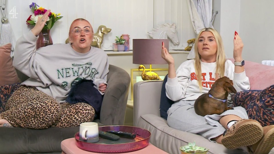 Two women sitting on a couch, reacting angrily.