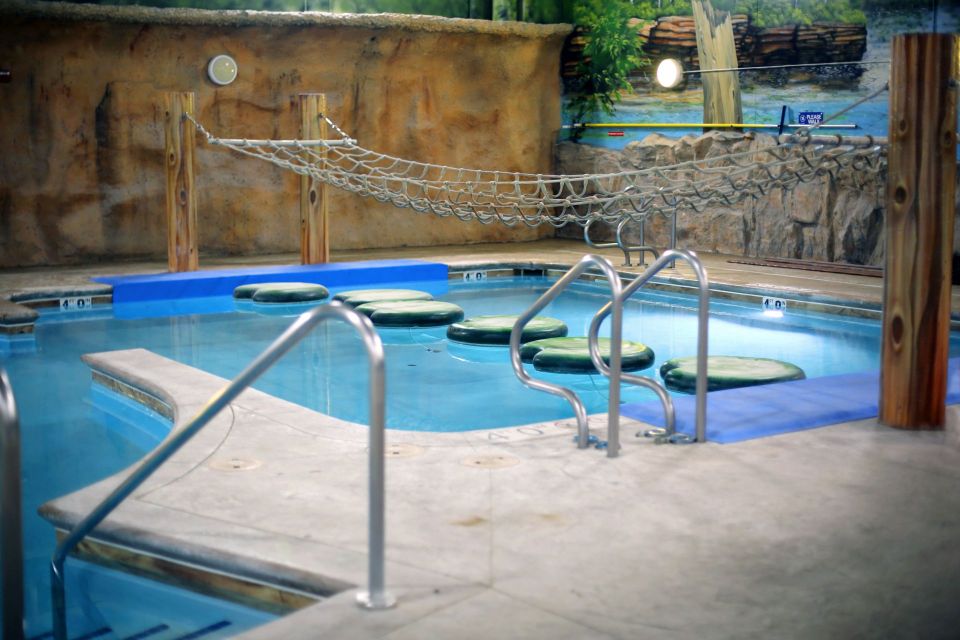 Indoor pool with lily pad stepping stones and a rope bridge.