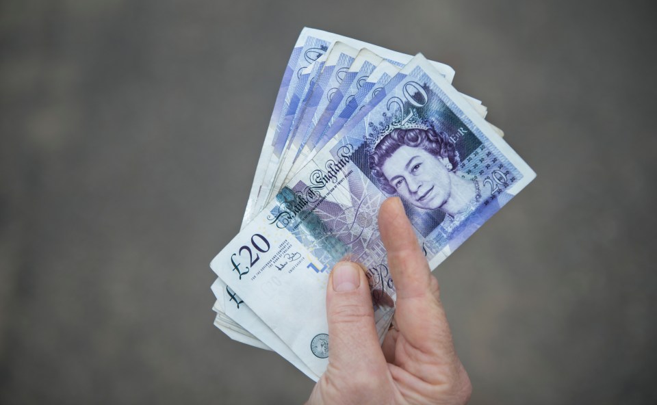 Hand holding a fan of British twenty-pound notes.